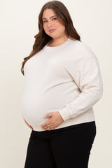 woman wearing a cream maternity plus oversized sweatshirt and posing with her baby bump