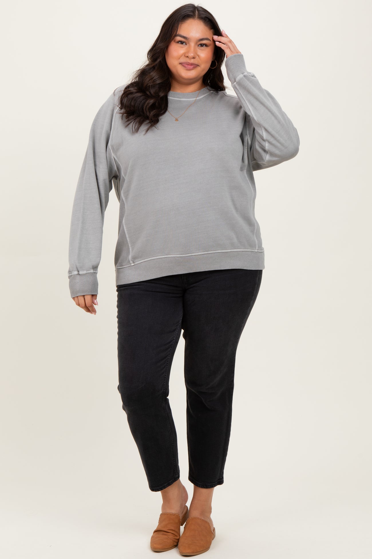 woman wearing a gray oversized sweatshirt paired with black cropped jeans and brown slip-on shoes