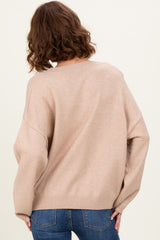 woman wearing a soft beige oversized sweater with a relaxed fit, styled with blue jeans, seen from the back