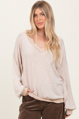 woman wearing a beige oversized v-neck long sleeve top with loose sleeves and side pockets