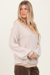 woman wearing a beige oversized v-neck sweater with wide sleeves and a relaxed fit
