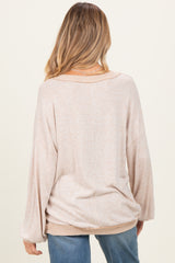 woman wearing a light beige oversized maternity sweater, shown from the back, with relaxed sleeves and a casual fit