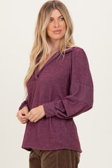 woman wearing a maroon long sleeve top with a v-neck and puffed sleeves
