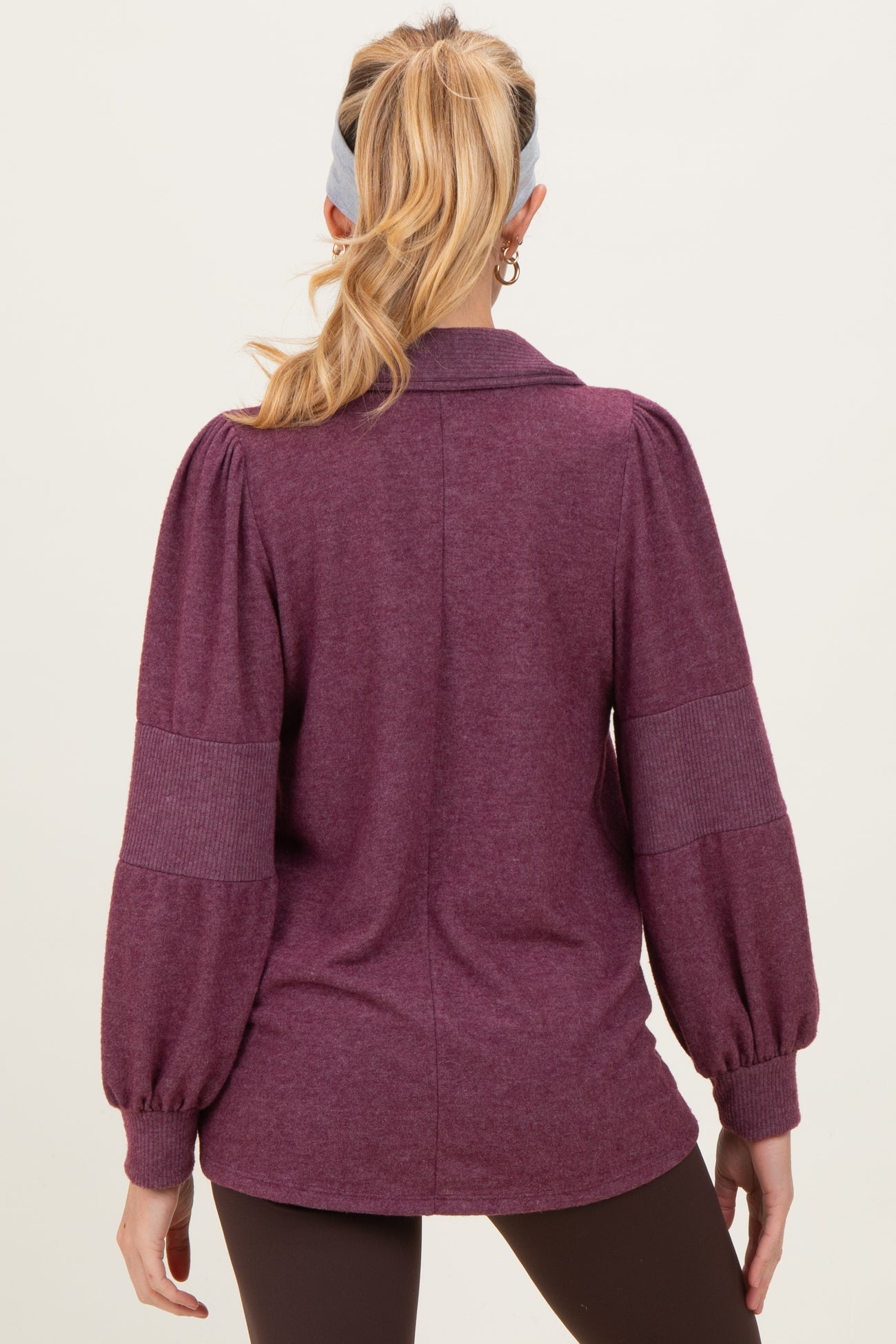 woman wearing a maroon maternity sweater with puffed sleeves, viewed from the back