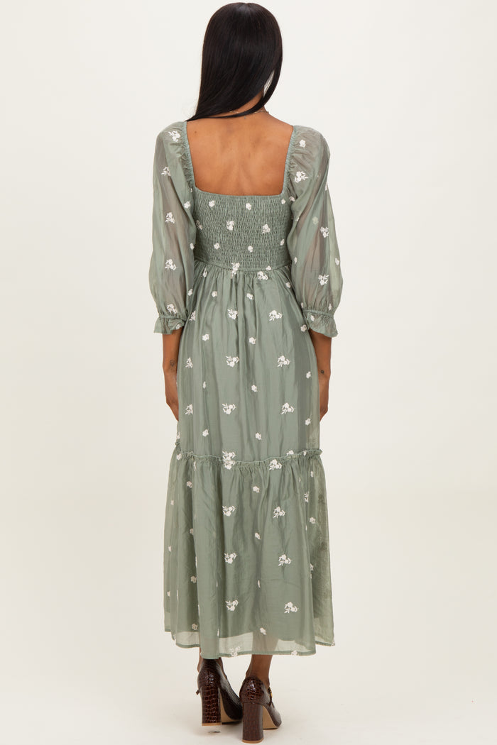 woman wearing a green embroidered maxi dress with puff sleeves and a tiered skirt, viewed from the back