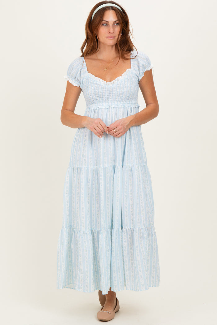 woman wearing a light blue tiered maxi dress with short puff sleeves and a smocked bodice