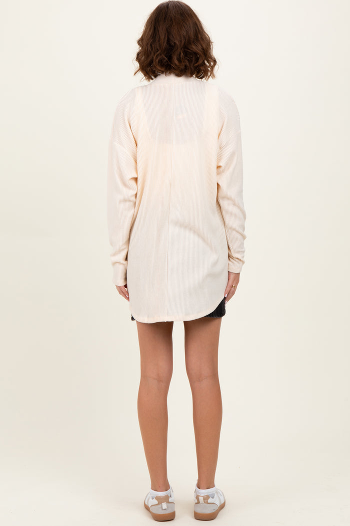woman wearing a light cream long sleeve ribbed tunic with a relaxed fit, shown from the back
