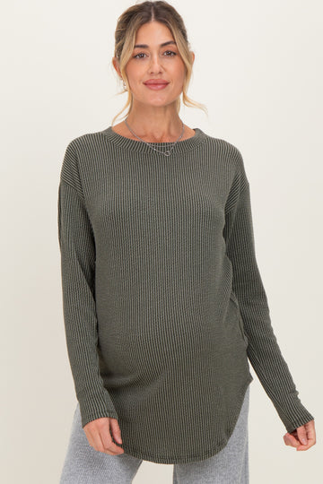 woman wearing a dark green ribbed maternity top with a rounded hem and long sleeves, showcasing her baby bump