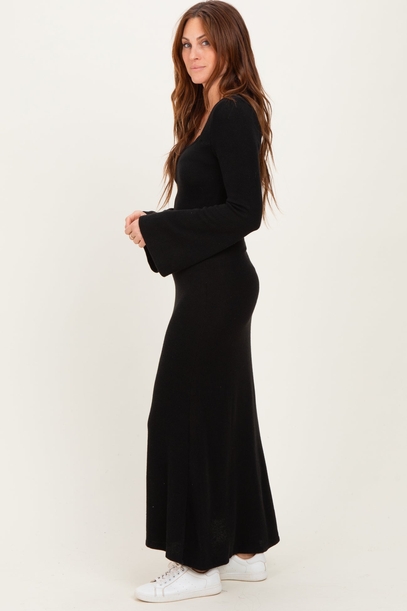 woman wearing a black long sleeve ribbed maxi dress with flared sleeves and white sneakers
