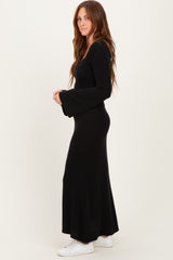 woman wearing a black long sleeve ribbed maxi dress with flared sleeves and white sneakers