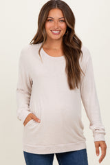 woman wearing a light pink maternity sweater with long sleeves and a front pocket, showing her baby bump
