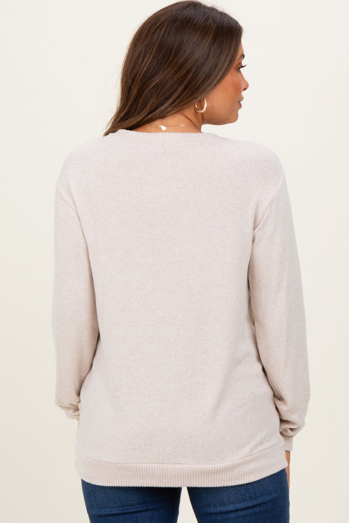 woman wearing a light beige maternity sweater with long sleeves, shown from the back