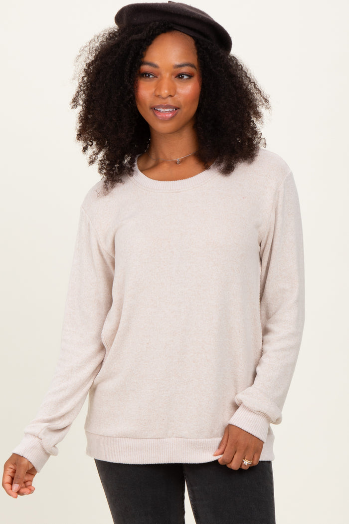 woman wearing a beige long sleeve sweater with a relaxed fit and ribbed hem, styled with a black hat