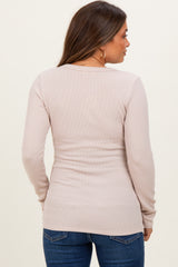 woman wearing a light pink long sleeve maternity top, seen from the back, paired with dark blue jeans