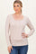 woman wearing a beige long sleeve henley top with button details and a scoop neckline paired with blue jeans