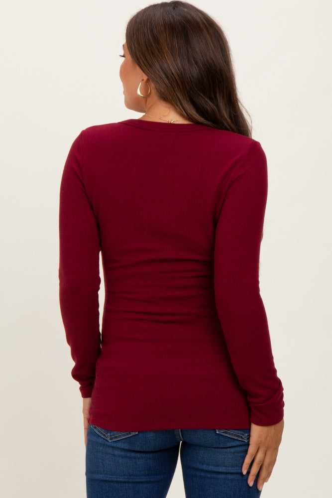 woman wearing a burgundy long sleeve maternity top, seen from the back, paired with blue jeans