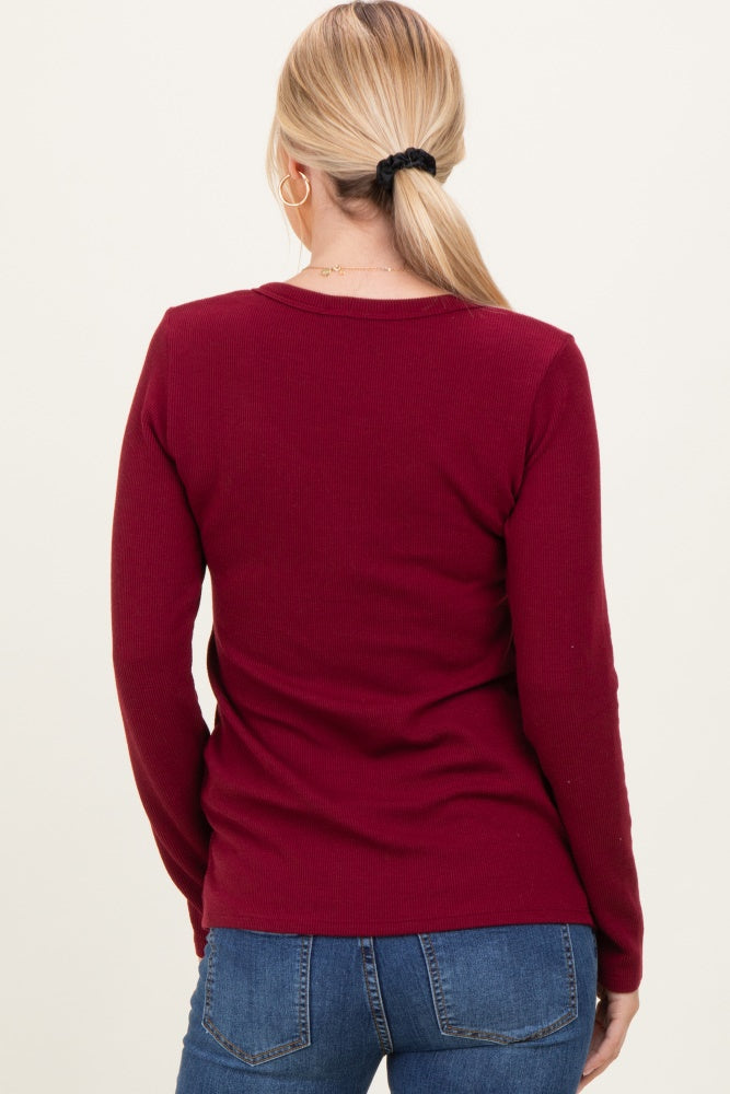 woman wearing a burgundy ribbed long sleeve top, viewed from the back, paired with blue jeans