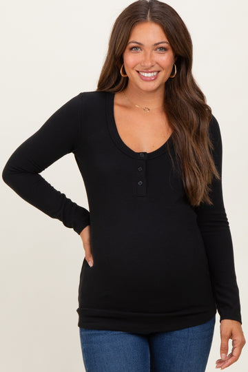 woman wearing a black long sleeve maternity top with a scoop neck and button details, showing her baby bump