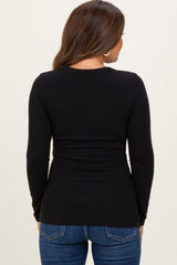 woman wearing a black long sleeve maternity top, seen from the back, paired with blue jeans