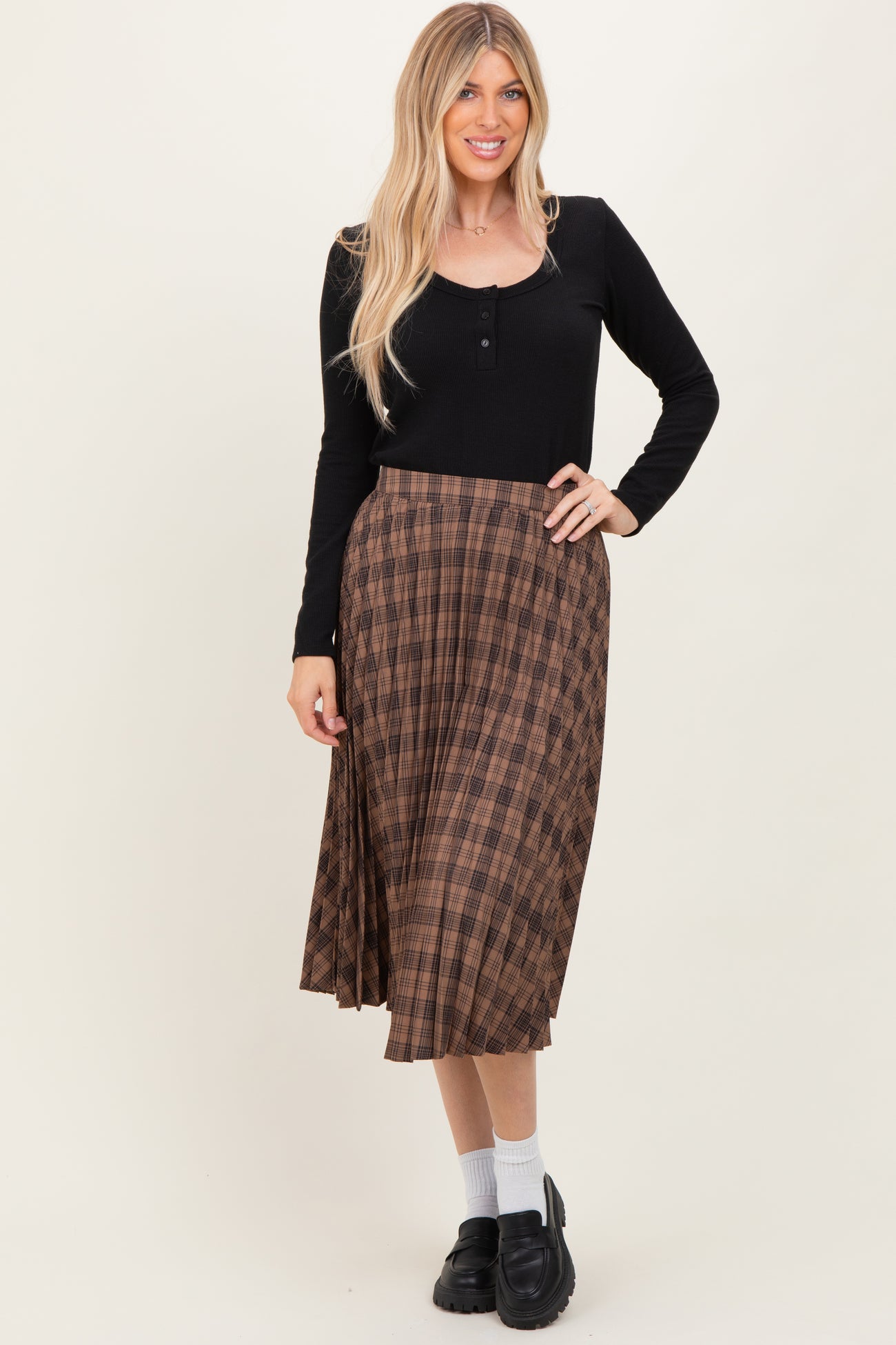 woman wearing a black long sleeve henley and a brown plaid midi skirt