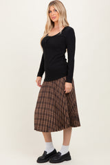 woman wearing a black ribbed long sleeve top and a brown check pleated skirt