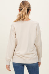 woman wearing a beige oversized maternity sweatshirt with long sleeves, seen from the back