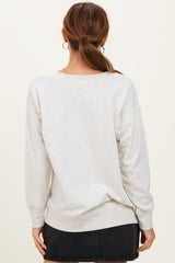 woman wearing a light gray oversized sweatshirt with drop shoulders and long sleeves, facing away from the camera
