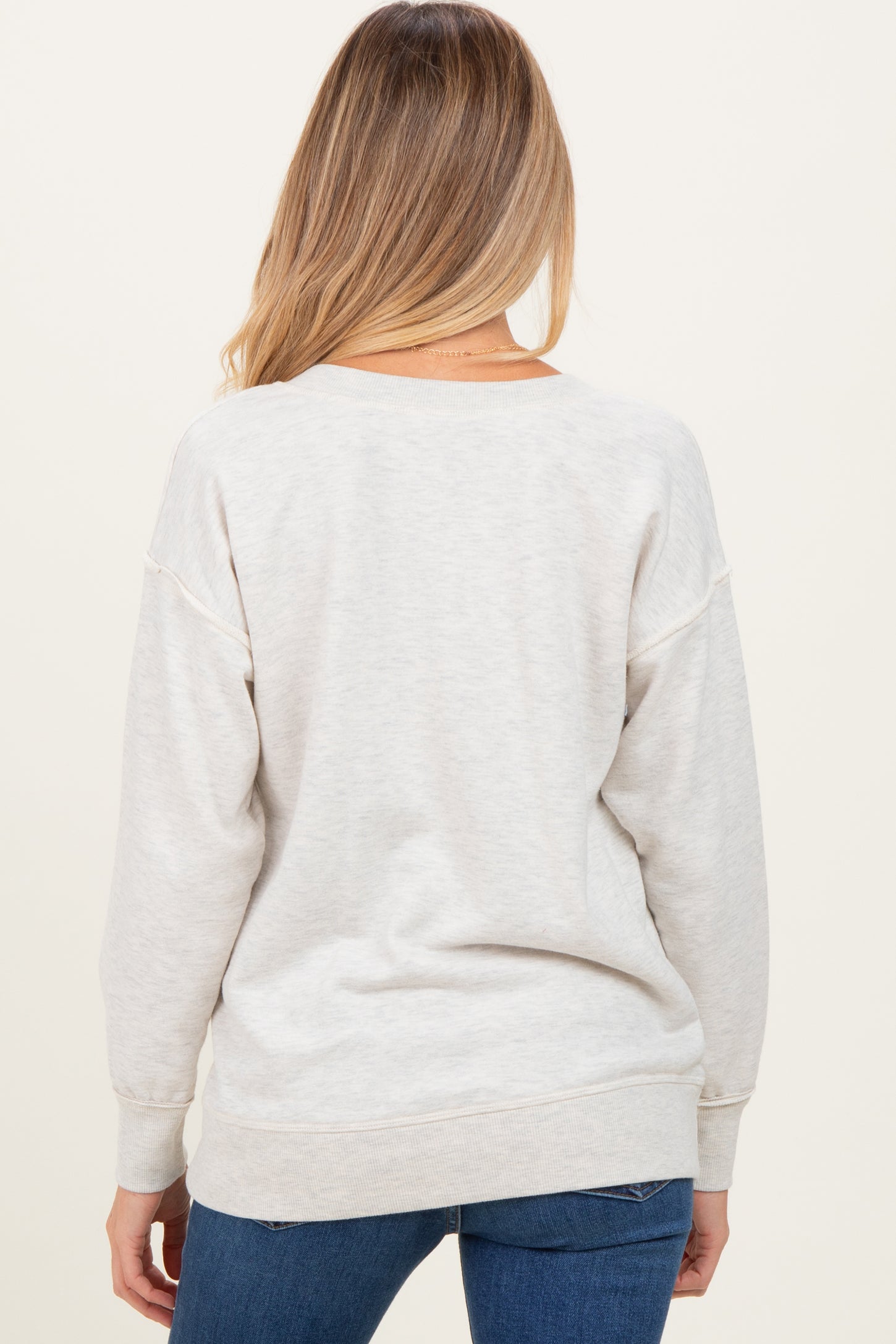 woman wearing a light gray maternity sweater with a relaxed fit, seen from the back with long sleeves
