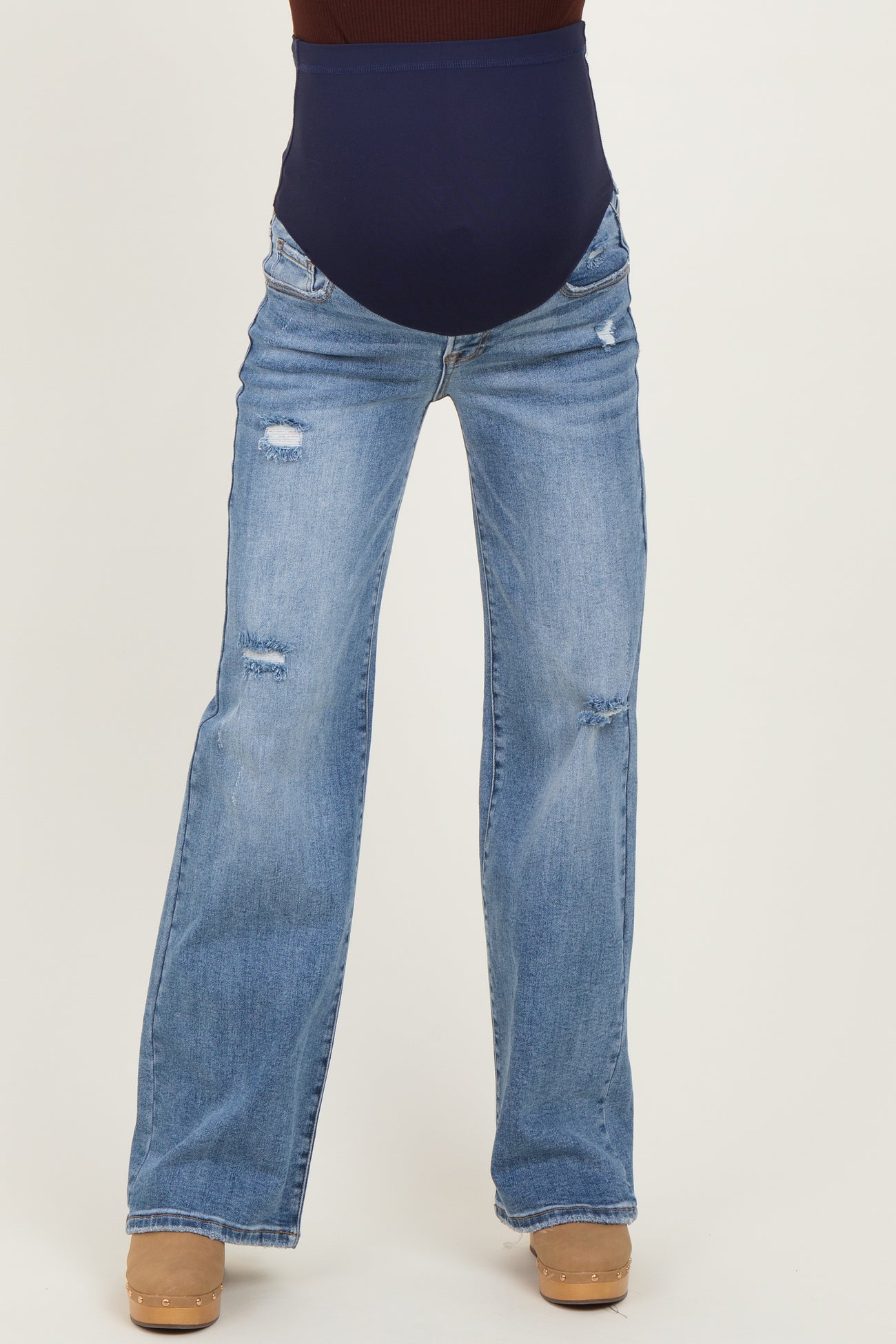 woman wearing distressed light blue maternity jeans with a navy blue over-the-bump panel