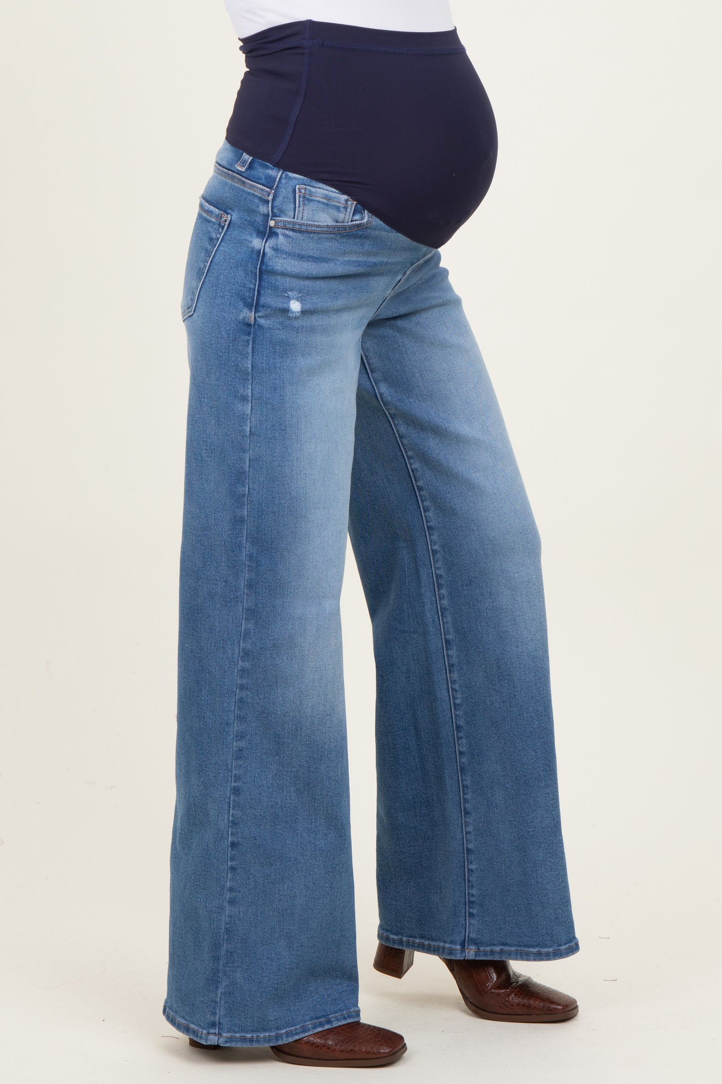 woman wearing a pair of light blue maternity wide leg jeans with a supportive belly panel and visible baby bump