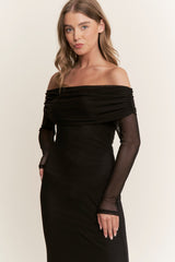 woman wearing a black off-the-shoulder dress with sheer long sleeves and a fitted silhouette