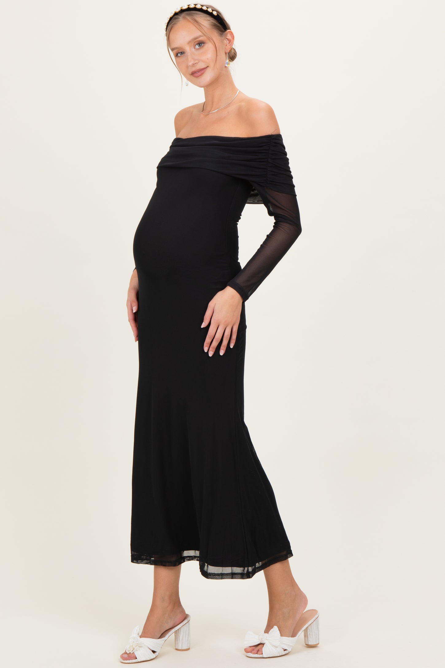 woman wearing a black off-shoulder maternity dress with long sleeves and a visible baby bump