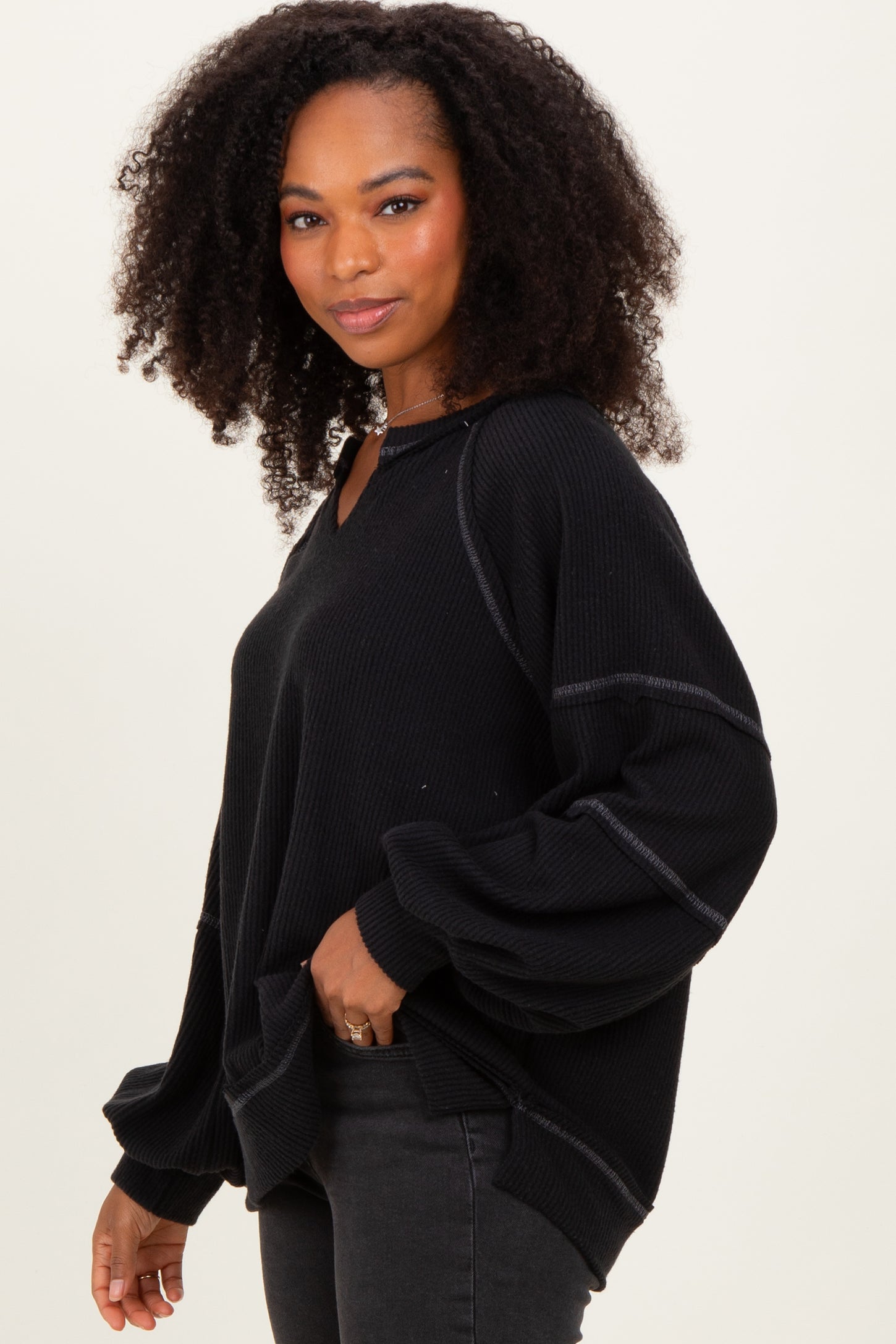 woman wearing a black oversized waffle knit sweatshirt with side pockets and balloon sleeves