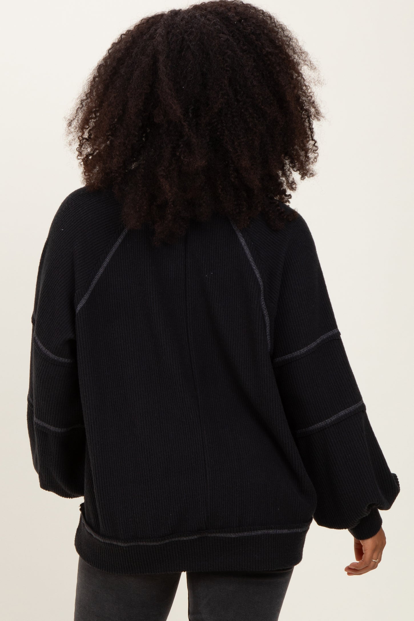 woman wearing a black oversized ribbed sweater with puff sleeves viewed from the back