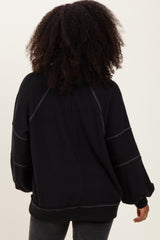woman wearing a black oversized ribbed sweater with puff sleeves viewed from the back