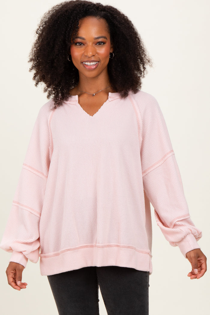 woman wearing a light pink ribbed oversized pullover sweater with a v-neck and balloon sleeves