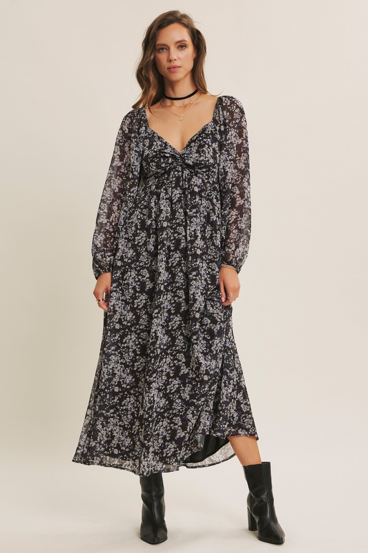 woman wearing a black floral maxi dress with long sleeves and a v-neckline, styled with black ankle boots