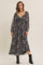 woman wearing a black floral maxi dress with long sleeves and a v-neckline, styled with black ankle boots