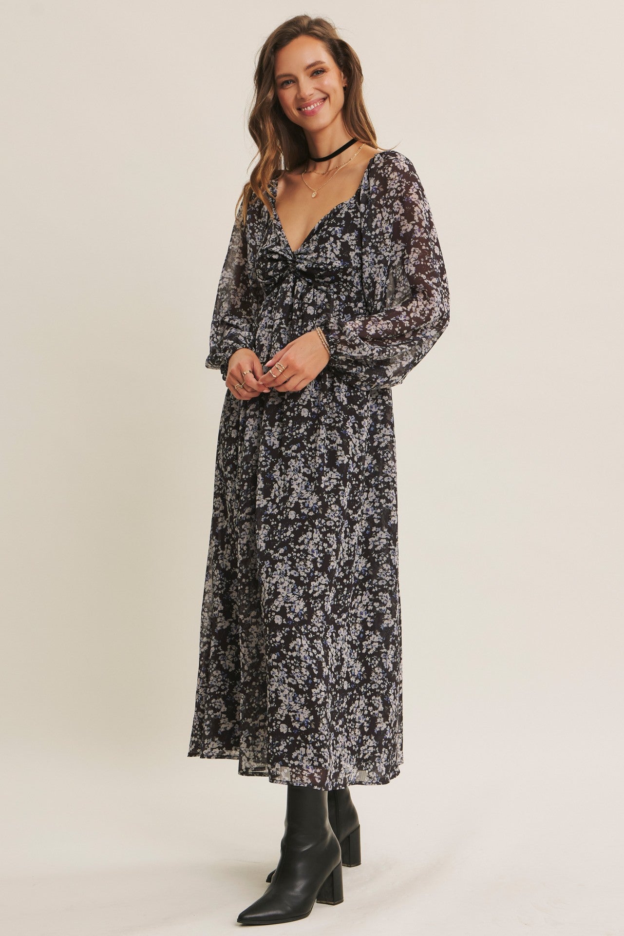 woman wearing a black floral long sleeve maxi dress with a deep v-neck and a tie detail at the waist