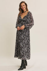 woman wearing a black floral long sleeve maxi dress with a deep v-neck and a tie detail at the waist