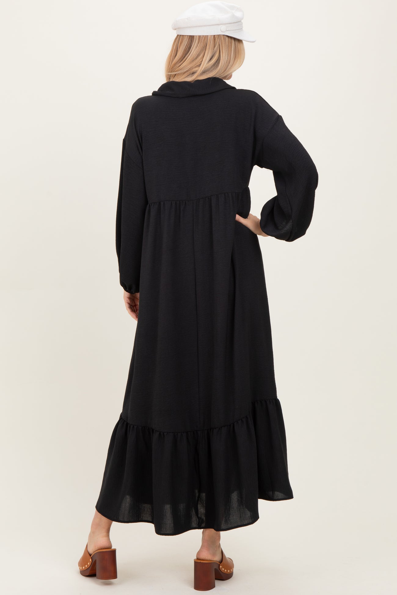 woman wearing a black long sleeve maxi dress with a tiered ruffle hem and a relaxed fit, viewed from the back