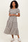 woman wearing a black and white striped tiered midi dress with short puff sleeves and white sneakers