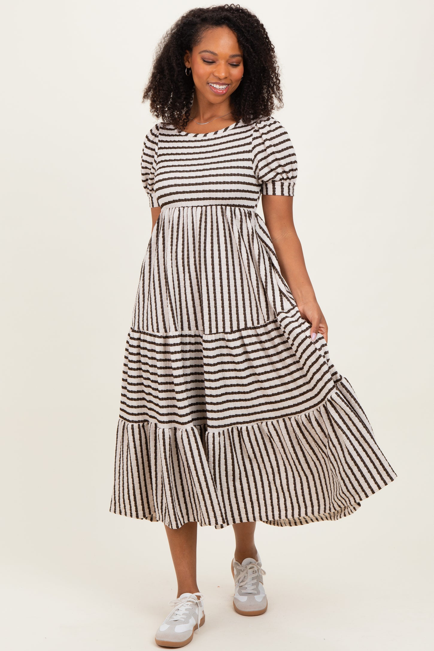 woman wearing a black and white striped tiered maxi dress with puff sleeves and white sneakers