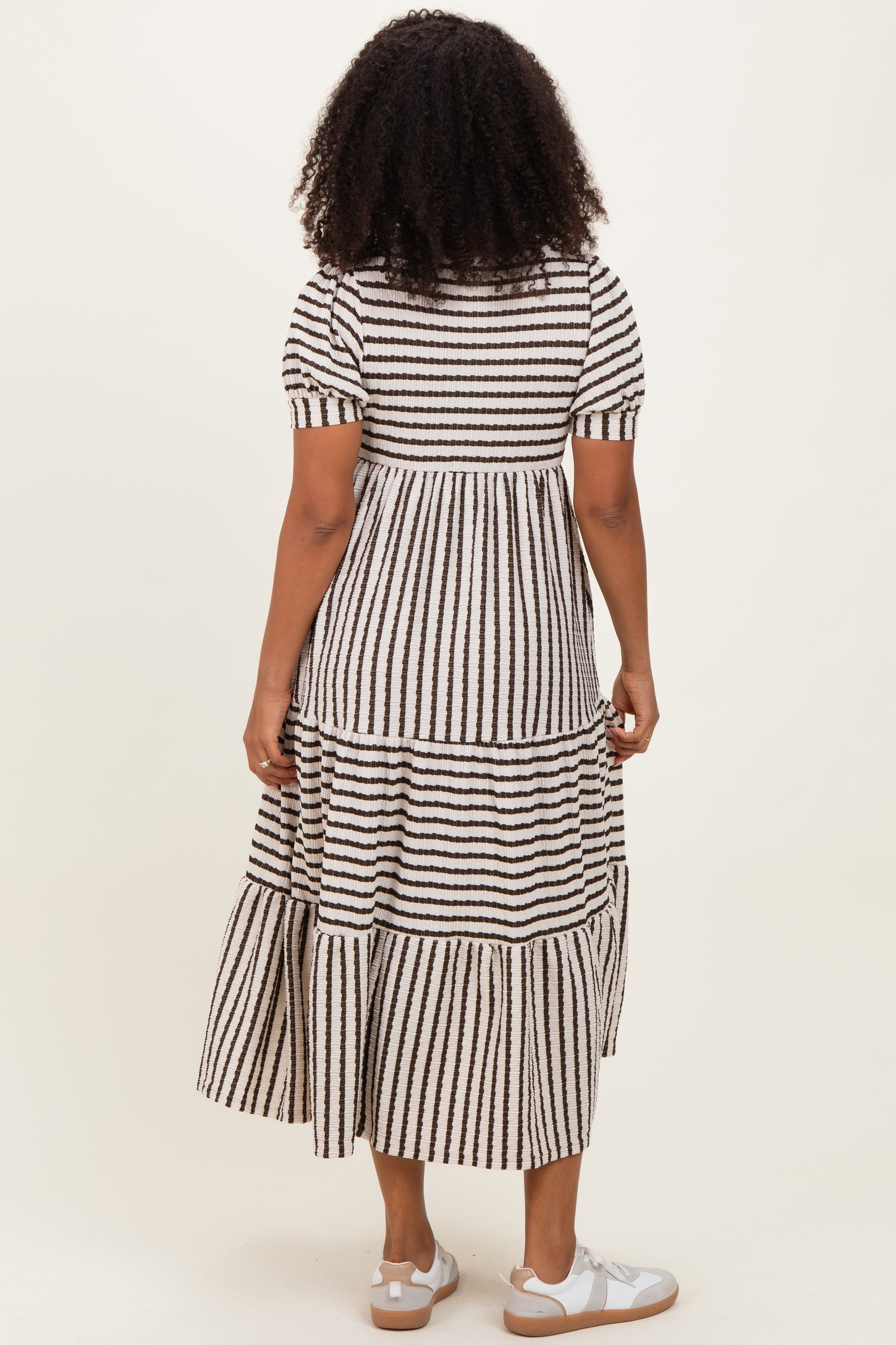 woman wearing a tiered black and white striped maxi dress with short sleeves, view from the back