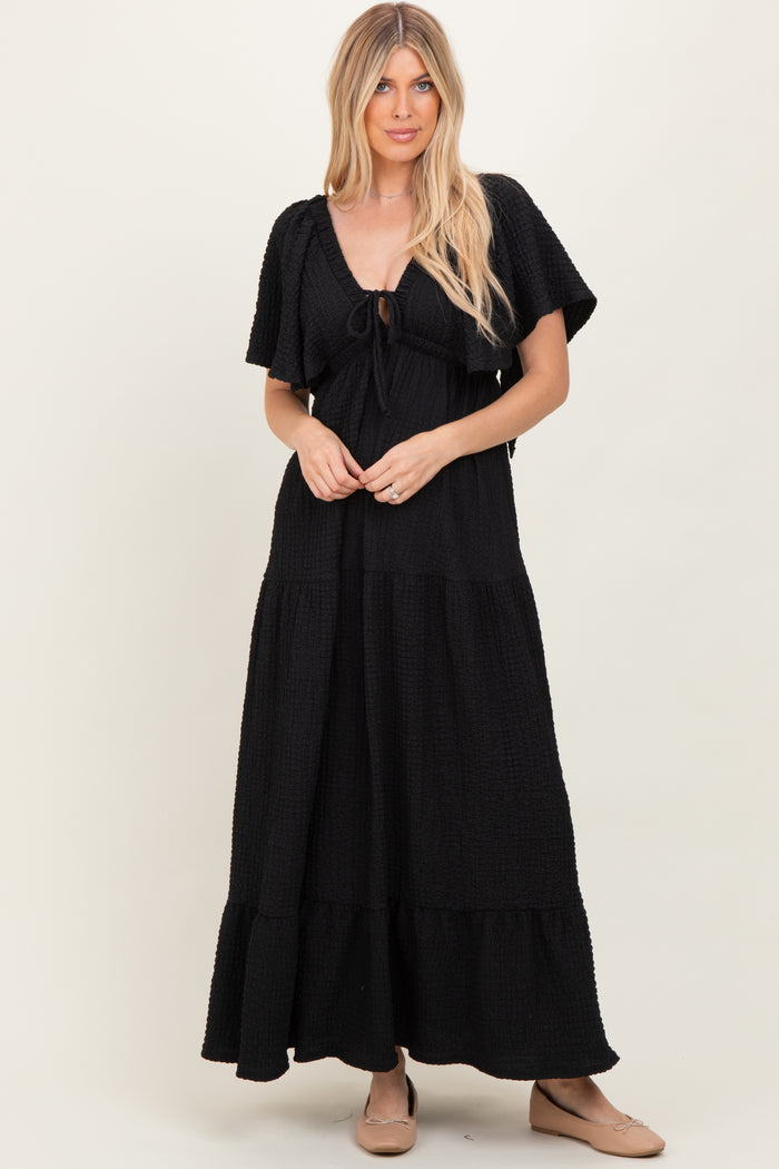 woman wearing a black tiered maxi dress with short sleeves and a tie front detail