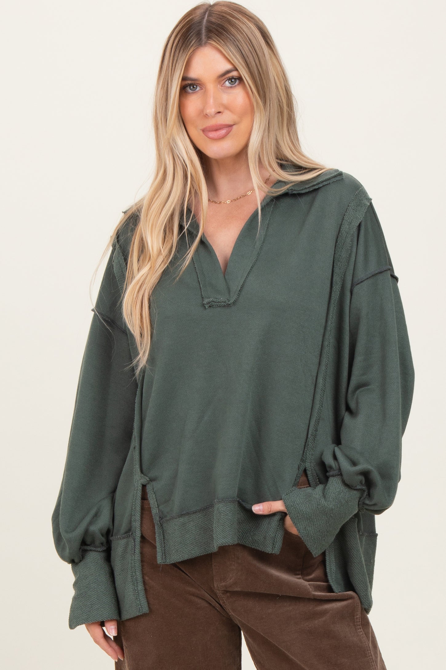 woman wearing a dark green oversized pullover sweater with a v-neck and long sleeves