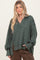 woman wearing a dark green oversized pullover sweater with a v-neck and long sleeves