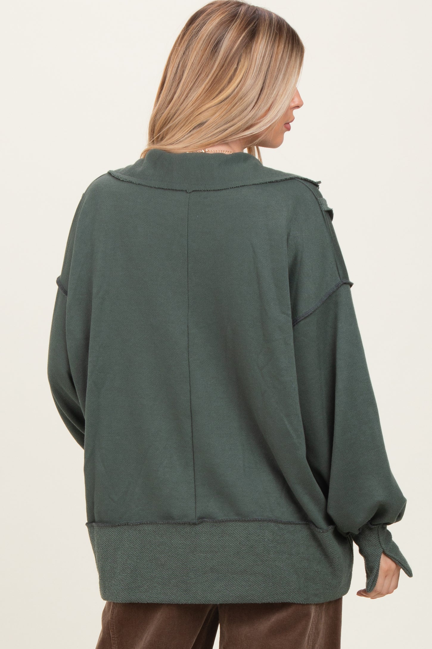 woman wearing a dark green oversized sweater with a relaxed fit and dropped shoulders, seen from the back