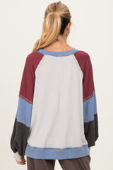 woman wearing a maternity color block long sleeve top in gray, maroon, blue, and black with a relaxed fit and balloon sleeves
