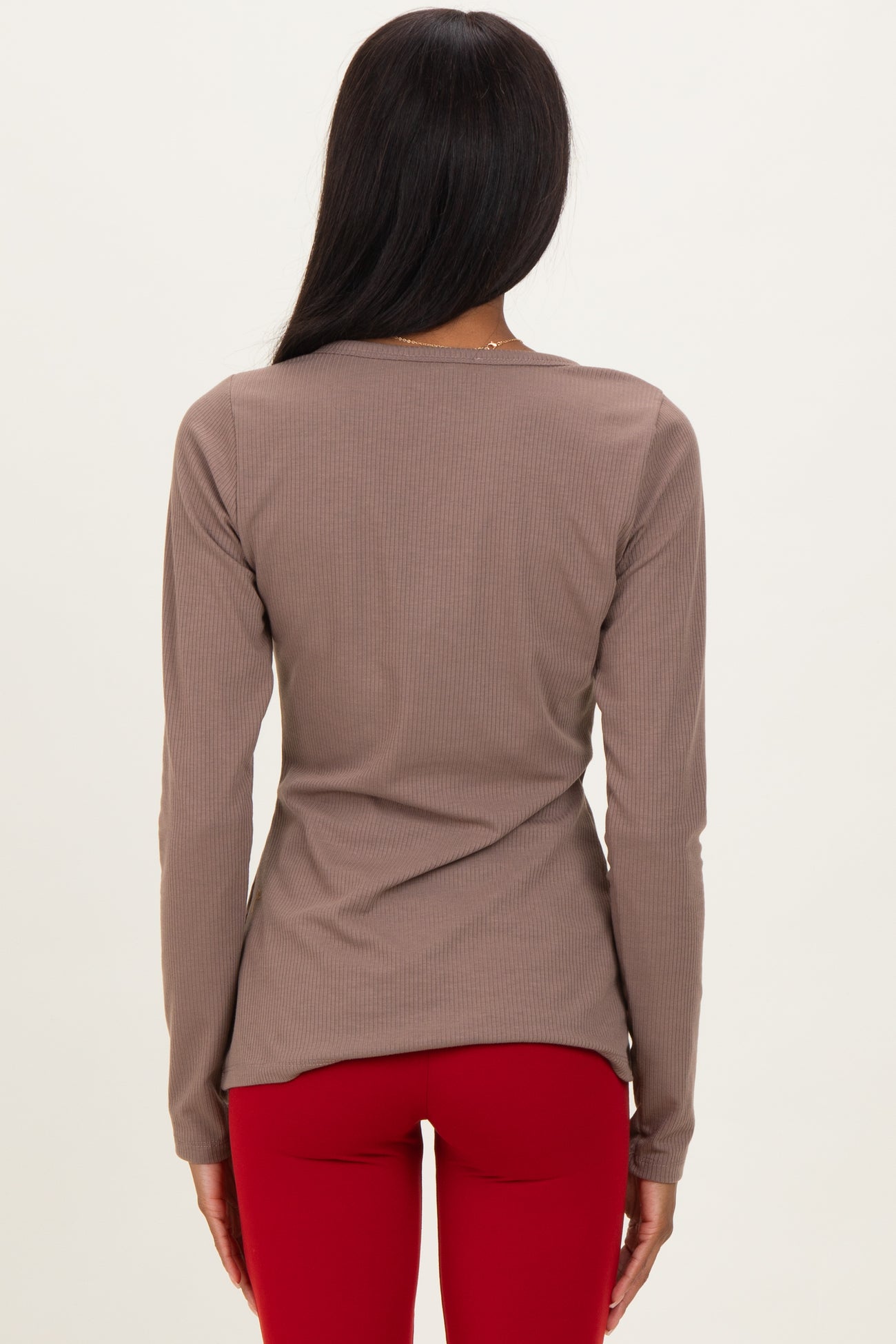 woman wearing a taupe long sleeve ribbed top and red leggings, shown from the back